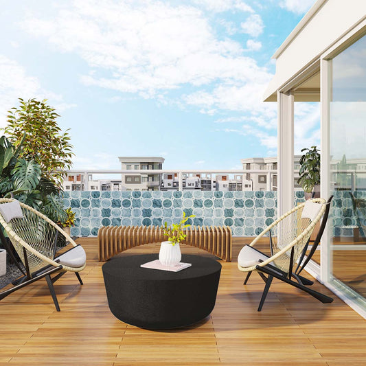 Outdoor lounge area featuring the Huron Small Concrete Table by Mobius Concrete, crafted from lightweight GFRC concrete in a Obsidian Night finish, surrounded by woven lounge chairs and modern tile flooring.