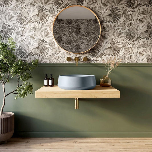 Santa Cruz round concrete sink shown installed in a bathroom with botanical wallpaper and wood vanity.